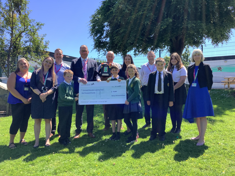 Cheque presentation featuring L-R: Finlay’s Mum, Donna McGrath (First Aid Instructor at Penrice), Nathan Cooper (Teacher at Luxulyan), Ewan (Year 5 at Luxulyan), Mr Henry Orchard, Geoff Brown (Chair of Trust Board at Cornwall Education Learning Trust), Oliver (Year 6 at Luxulyan), Emma Williams (Headteacher at Luxulyan), Flora (Year 5 at Luxulyan), Finlay’s Dad, Finlay, Finlay’s Sister, Lucy Gambier (Head of School at Penrice).